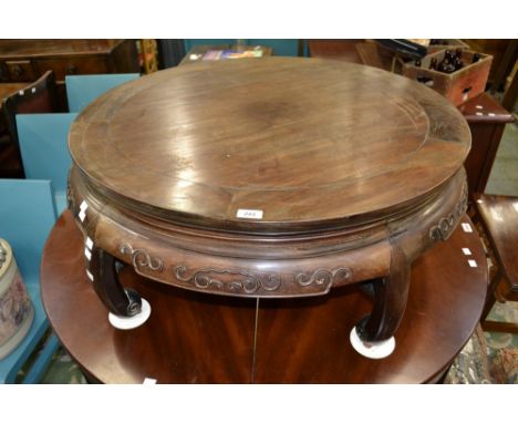 A Chinese hardwood low circular occasional table, shaped frieze carved in relief, scroll feet, 36cm high, 90cm wide