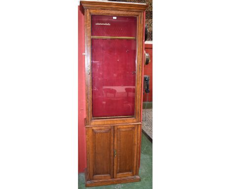 An Edwardian oak gun cabinet, made by Army and Navy CSL (Co-operative Society Limited), glazed panel door, lined with red vel