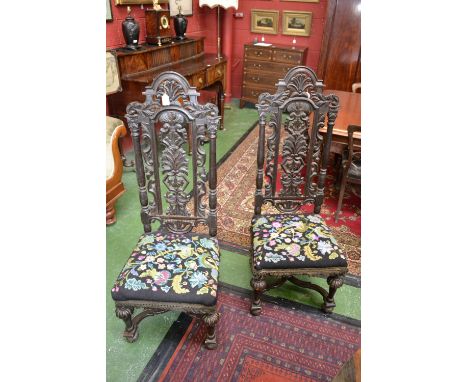 A pair of Carolean revival high back dining chairs profusely carved backs, woolwork stuffed seats, lobed forelegs, serpentine