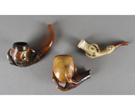Two carved meerschaum pipe bowls, both bowls carved with claws and eggs, one with curved amber stem and mouthpiece, together 