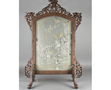 A Chinese hardwood mirror back fire screen, the frame carved with grape and vine decoration on scroll bracket feet, mirror he