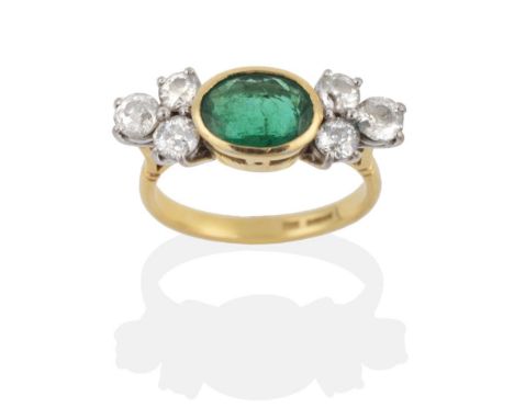 An 18 Carat Gold Emerald and Diamond Ring, an oval cut emerald in a rubbed over setting and spaced by groups of three round b