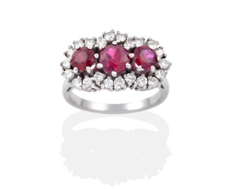 A Ruby and Diamond Cluster Ring, three graduated round cut rubies within a border of round brilliant cut diamonds, to taperin