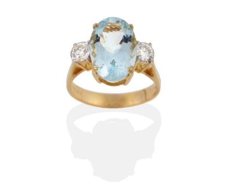 An 18 Carat Gold Aquamarine and Diamond Three Stone Ring, an oval cut aquamarine spaced by round brilliant cut diamonds in cl