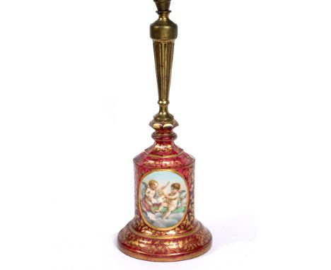 A LATE 19TH CENTURY BOHEMIAN CRANBERRY GLASS TABLE LAMP, the gilded decoration reserving an oval panel painted with two putti
