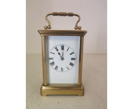 A French brass carriage clock with enamel dial, Roman Numerals to face 11cm high, bevelled glass to four sides with oval beve