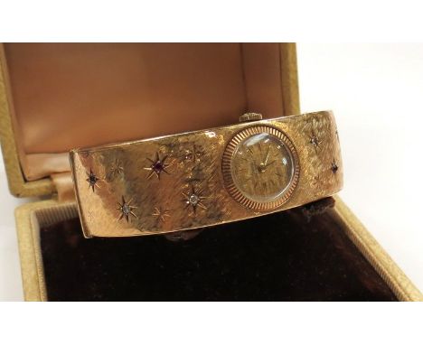 A 9ct gold stiff hinge watch bangle set with diamond and ruby in star settings,  38.9g total 