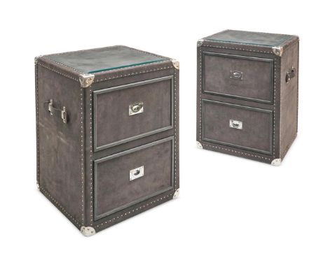 A PAIR OF GREY SUEDE COVERED BEDSIDE TRUNKS BY GUINEVEREEach with glass inset tops above two drawers, strap handles and silve