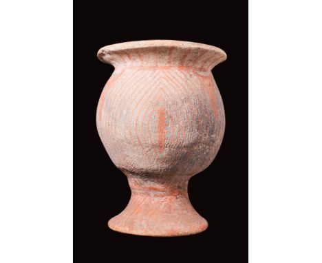 Ca. 300 BC - AD 400.A pottery jar with a bulbous body supported by an elevated foot. Its surface is adorned with a mesmerisin