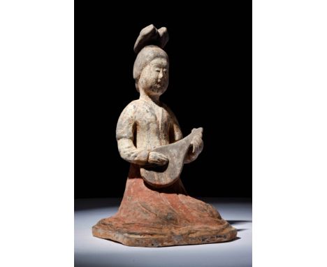 Ca. AD 600 -700.A pottery figure representing a seated female musician playing a string instrument. The woman is depicted sea