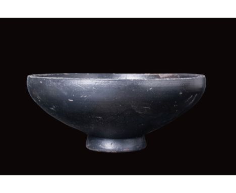 Ca. 400 - 300 BC.A black-glazed plate with a broad basin tapering to a short foot base, fully covered in a lustrous black gla