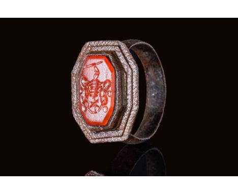 Ca. AD 1500.A ring with a rectangular octagonal bezel set with a carnelian intaglio engraved with a central shield flanked by