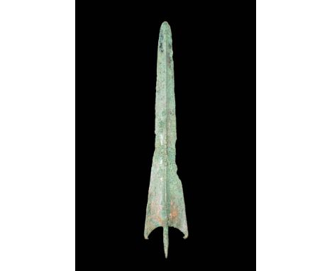 Ca. mid-6th century BC.A bronze spearhead with a long blade that tapers gracefully to a sharp point. Its shoulders are with i