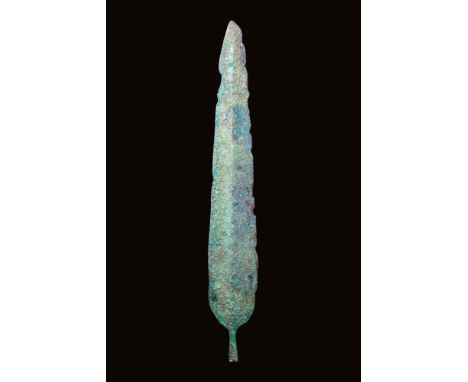 Ca. 2nd - 1st millennium BC.A cast bronze spearhead featuring an elongated, leaf-shaped blade, tapering sharply to a point. A