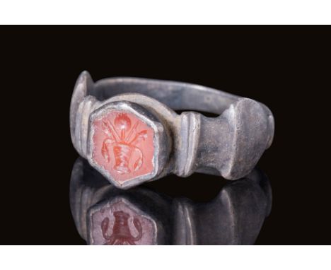 Ca. AD 1 - 300.A silver finger ring with a flat-section hoop transitioning into amphora-shaped shoulders. These shoulders sup