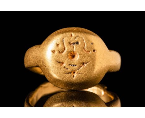 Ca. AD 800 - 1200.A 21.5 ct gold ring with a round band, expanding at the shoulders and a large bezel engraved with a script 