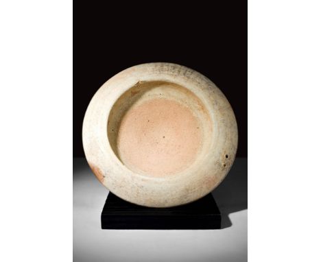 Ca. 300 BC.A terracotta dish with a flat base and a shallow basin bordered by a rounded flange. The flange is accented by two