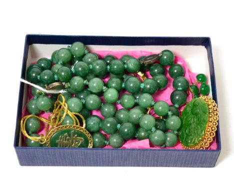 A carved jade brooch in a frame stamped '585', a pair of jade set screw back earrings, stamped '14k', a jade pendant in a gil