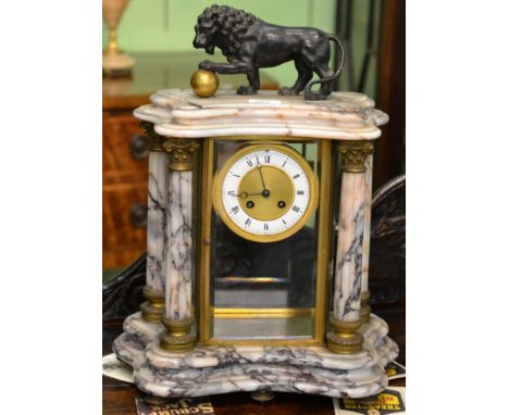 A marble four glass striking mantel clock, surmounted by a lion