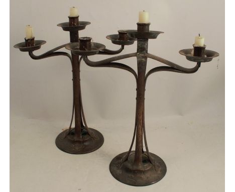 A pair of Arts and Crafts copper candlesticks, with central candle holder and two open work branches holding two further cand