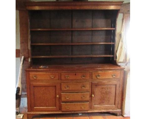 A Georgian cupboard dresser, with an associated close boarded Delft rack over three frieze drawers, with a central section of