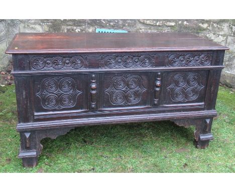 An antique oak blanket box, with roundel carved front and plain rising lid, raised on bracket feet