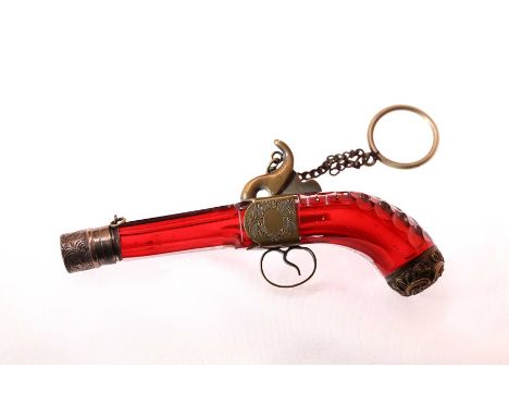 A novelty ruby red scent bottle, in the shape of a pistol, a registration mark on the trigger guard, length 5.75ins x width 1