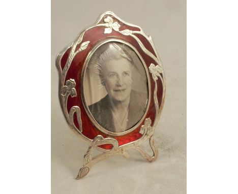A silver and enamel Art Nouveau photograph frame, of oval form, the frame decorated with Iris's and red enamel, af, with ease