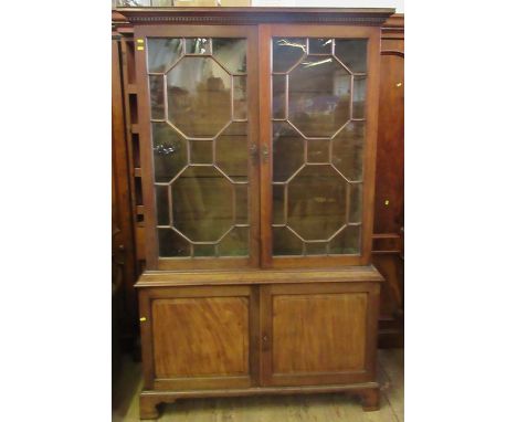 A Georgian style mahogany bookcase cupboard, having a pair of astragal glazed doors to the upper section, with four adjustabl
