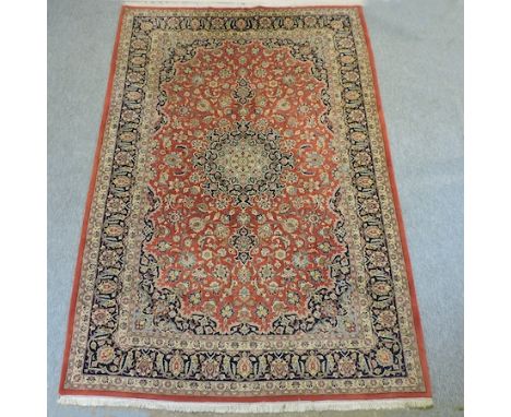 A Keshan carpet, with a central medallion and floral design, on a red ground, 310 x 203cm