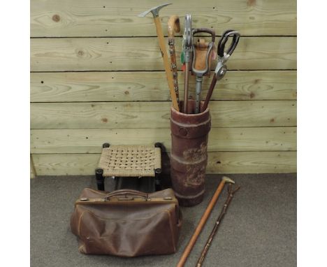 A leather stick stand, containing a collection of various walking sticks, together with a Gladstone bag and a stool