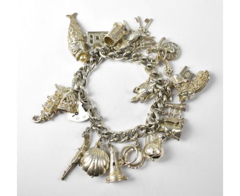 A hallmarked silver charm bracelet with heart clasp and approximately eighteen silver charms to include a boot, vintage bicyc