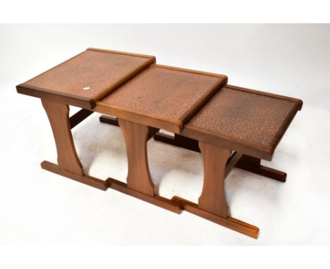 E GOMME LTD OF LONDON FOR G-PLAN a vintage retro teak framed nest of tables, each with inset beaten copper panel to the top, 