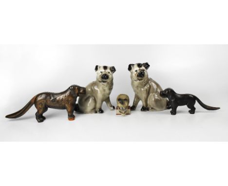 A pair of late 19th century ceramic models of pugs, height 19.5cm, a bisque candle holder in the form of a skull on a book an