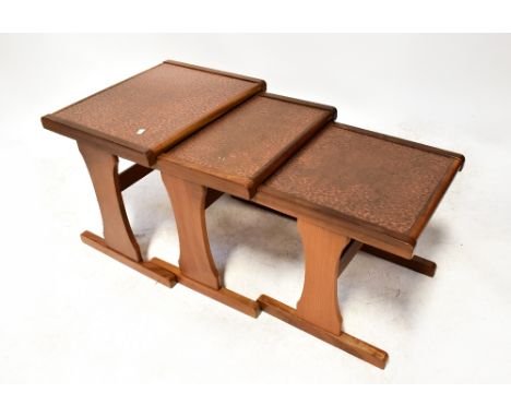 E GOMME LTD OF LONDON FOR G-PLAN; a vintage retro teak framed nest of tables, each with inset beaten copper panel to the top,