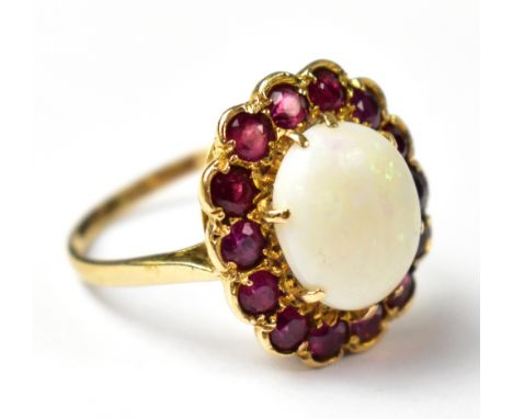 A late 19th/early 20th century 9ct gold opal and ruby cluster ring, the central claw set oval opal with flashes of green in a