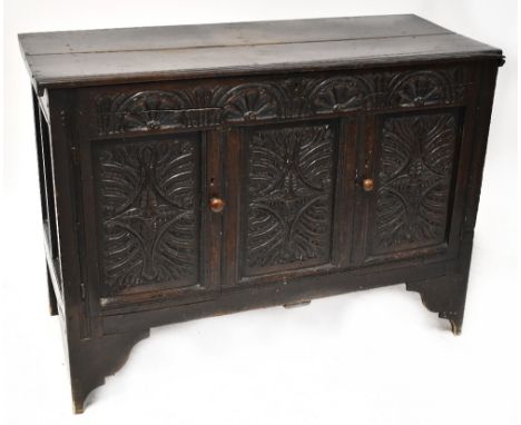 An 18th century oak mule chest with plank top above carved front, the frieze with flower and foliate motifs, above a pair of 
