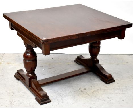 An early 20th century mahogany crossbanded draw-leaf dining table, raised on turned baluster supports united by a stretcher, 