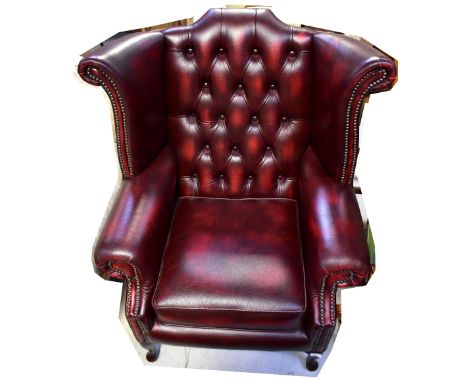 A contemporary oxblood leather button pressed wingback armchair raised on squat cabriole legs to pad feet. CONDITION REPORT O
