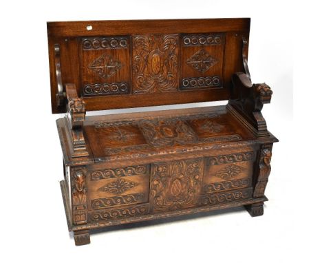 A late 19th/early 20th century oak monks' bench with three panels to the back and carved top rail, the seat with foliate and 