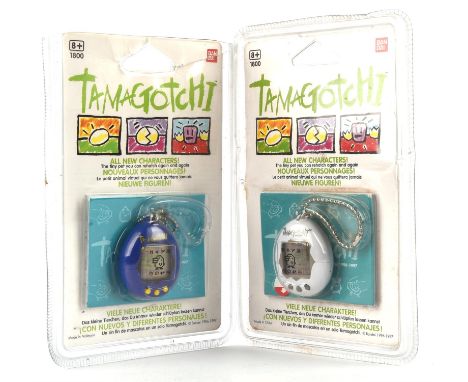 A lot containing 2 Bandai Tamagotchi - Original 1996/1997, includes the white and blue models The blue Tamagotchi has a tear 