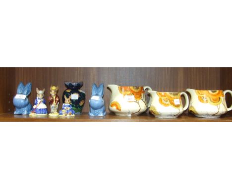 A set of three graduated Clarice Cliff Bizarre 'Rhodanthe' decorated jugs, 11cm, 10cm and 9cm high, two SylvaC blue-glazed ra
