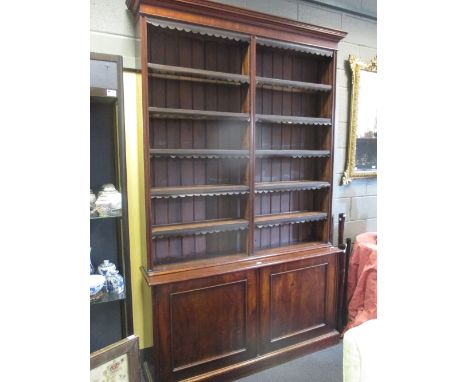 A 19th century mahogany bookcase, with raised boarded shelf back and later leather border decoration above a cupboard and on 