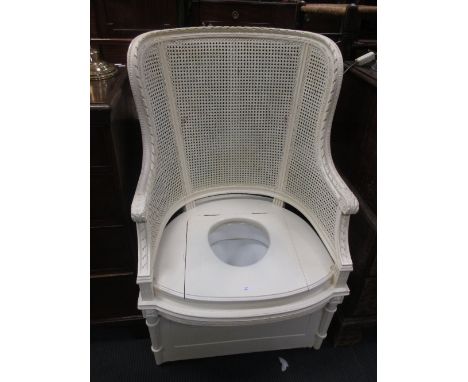 A commode in the form of a white painted bergere armchair  