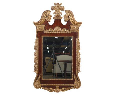 A GEORGE II STYLE PARCEL GILT WALNUT WALL MIRRORWith cartouche crest and broken arch pediment, 81cm wide; 153cm high