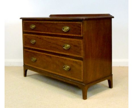 An Edwardian mahogany chest of three wide graduated drawers, with satinwood inlay to the fronts, shaped splashback and raised