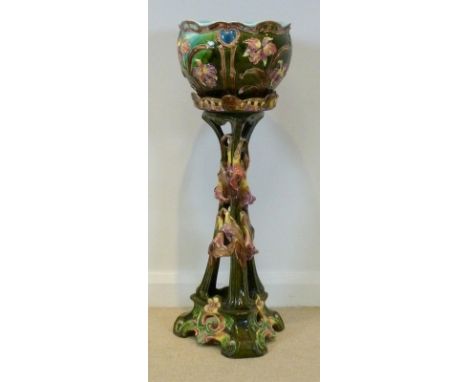 An Art Nouveau ceramic jardiniere and pierced stand, decorated with floral scrolling design including iris and convulvus agai