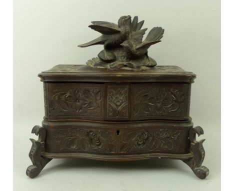 A Black Forest jewellery box, the top with finial of a pair of carved turtle doves, the tops and sides carved with leaves and