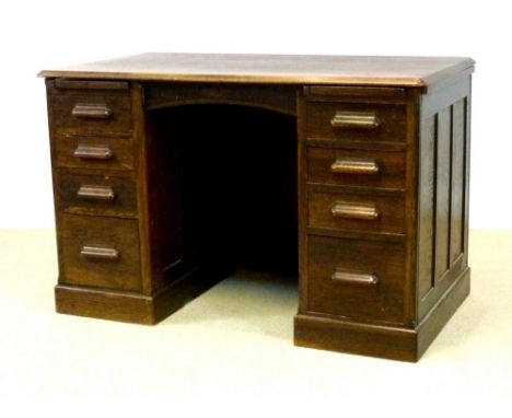 A mid 20th century oak pedestal desk with four graduated drawers to each pedestal and two sliders, with modesty panel, possib