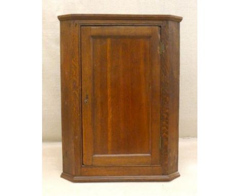 A Georgian oak wall hanging corner cupboard, with single plain panel door enclosing blue painted interior with two shelves, 6